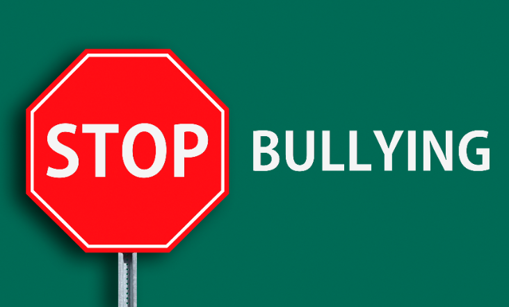 Red stop sign with the word "stop" next to the word "bullying". There is a green background.