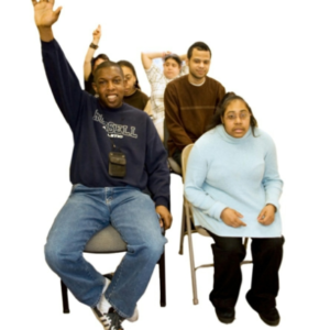 A group of self-advocates sitting in three rows of chairs. Two people have their hand raised.
